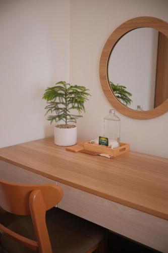 a wooden table with a mirror and a plant on it at Glory 2 Hue Homestay in Hue