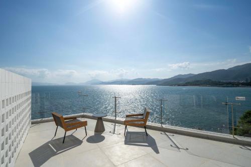 a balcony with a table and chairs and a view of the water at Shenzhen GuanHu Secret Wild Reef Seaview Hotel in Shenzhen