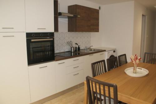 Il comprend une cuisine avec une table en bois et des placards blancs. dans l'établissement Escapade en bord de Dordogne, à Bourg
