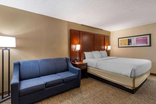 a hotel room with a bed and a blue couch at Comfort Inn Laurinburg in Laurinburg