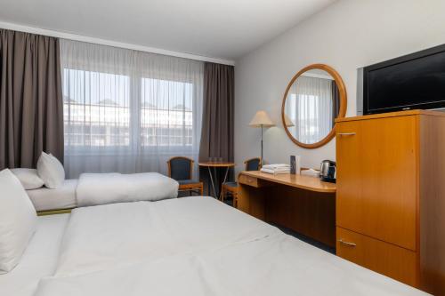 a hotel room with a bed and a desk and a mirror at OREA Hotel Voro Brno in Brno