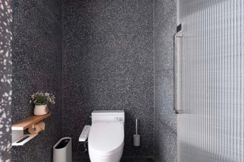 a bathroom with a white toilet in a black wall at Shenzhen GuanHu Secret Wild Reef Seaview Hotel in Shenzhen