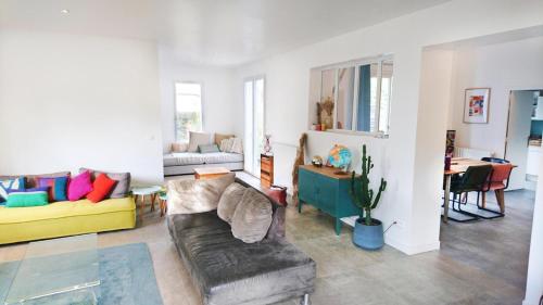 a living room with a couch and a table at Maison entre forêt et océan - piscine et tennis in Ondres