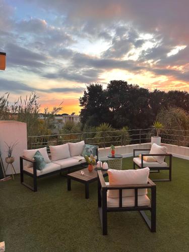 une terrasse avec des canapés et des tables et un coucher de soleil dans l'établissement VILLA RIVIERA - piscine, rooftop vue mer, à Six-Fours-les-Plages