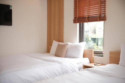 two beds in a room with a window at Glory 2 Hue Homestay in Hue