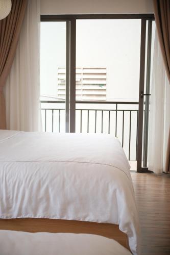 a bedroom with a white bed and a large window at Glory 2 Hue Homestay in Hue