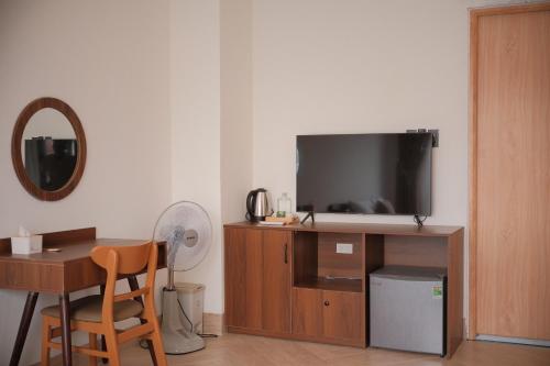 a living room with a tv and a desk with a chair at Glory 2 Hue Homestay in Hue