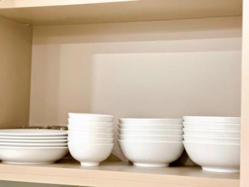 four white bowls are sitting on a shelf at Sóng Homestay-The Sóng Apartment Vũng Tàu Nghỉ Dưỡng Biển Cao Cấp 5 Sao- The Song Vung Tau Condotel 5 Star Beach View Apartment in Vung Tau