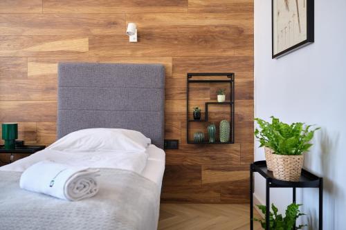 a bedroom with a bed with a wooden wall at Solny Square Aparthotel in Wrocław