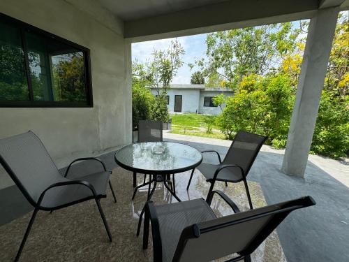 a patio with a glass table and chairs at Little Bird in Prachuap Khiri Khan