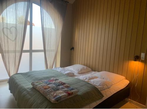 a bed in a bedroom with a large window at Gæstehusets lejlighed in Tarm