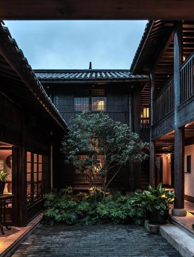 a building with a tree in the middle of a courtyard at Lijiang Old Town Lanshe hotel in Lijiang