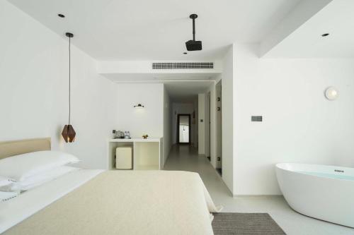 a bedroom with a white bed and a bath tub at Shenzhen GuanHu Secret Wild Reef Seaview Hotel in Shenzhen