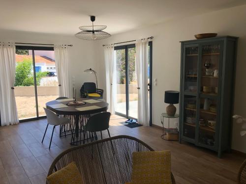un salon avec une table et des chaises de salle à manger dans l'établissement Maison neuve entre mer et forêt au calme, à Notre-Dame-de-Monts