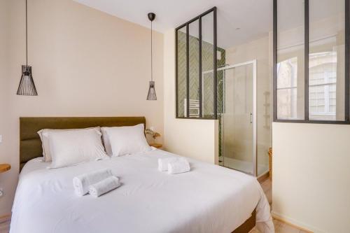 une chambre avec un lit blanc avec deux serviettes dessus dans l'établissement Charmant appartement en plein cœur de Bordeaux, à Bordeaux