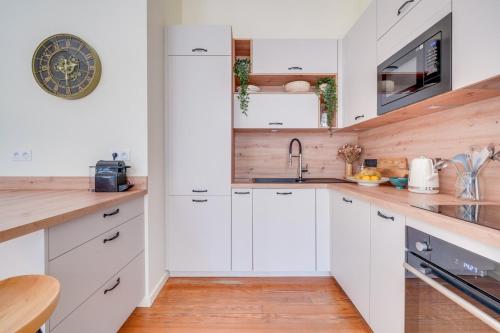 une cuisine avec des armoires blanches et un plancher en bois dans l'établissement Charmant appartement en plein cœur de Bordeaux, à Bordeaux