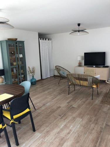 un salon avec une table, des chaises et une télévision dans l'établissement Maison neuve entre mer et forêt au calme, à Notre-Dame-de-Monts