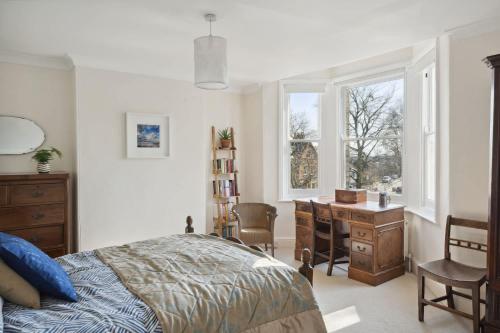 a bedroom with a bed and a desk and a window at Beautiful Victorian Home on Peaceful Green Square in Exeter