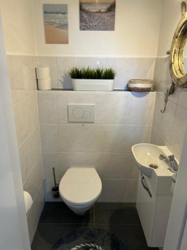 a white bathroom with a toilet and a sink at Haus am Meer in Dorum Neufeld
