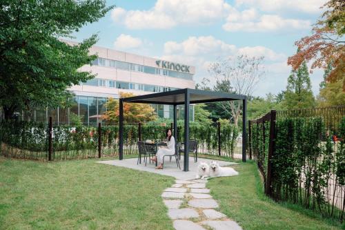 a woman sitting at a table in a gazebo with a dog at Kinock in Gyeongju