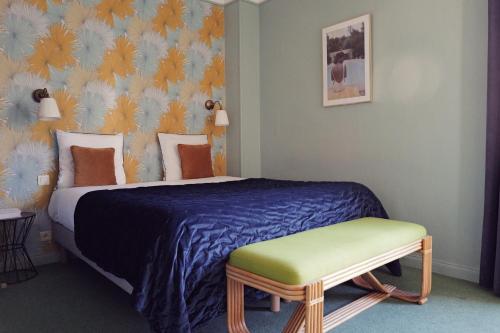 a bedroom with a bed with a blue blanket and a bench at Hôtel Azur in Reims