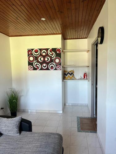 a living room with a couch and a painting on the wall at F2 à la campagne avec Piscine in Morne Baldara