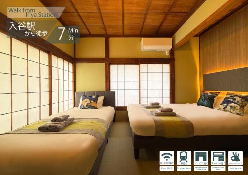 two twin beds in a room with windows at nestay villa tokyo ueno in Tokyo