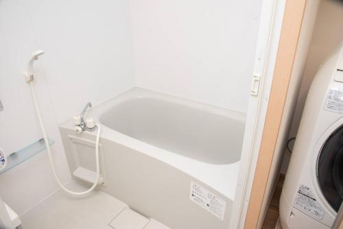 a white tub in a bathroom next to a washing machine at レーヴk402 in Makishimachi