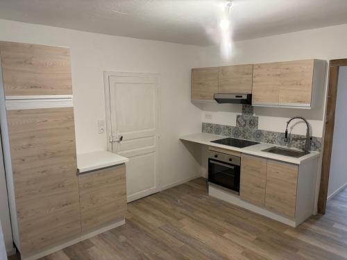 une cuisine avec des armoires en bois, un évier et une cuisinière dans l'établissement Charmante maison de village, à Masseube