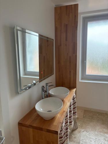 La salle de bains est pourvue de 2 lavabos sur un comptoir en bois avec un miroir. dans l'établissement Charmante maison de village, à Masseube