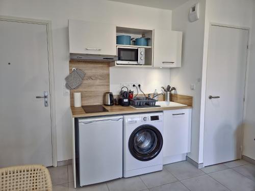 une cuisine avec un lave-linge et un micro-ondes dans l'établissement Kalia Residence New appartment with Terrace, à Cavalaire-sur-Mer