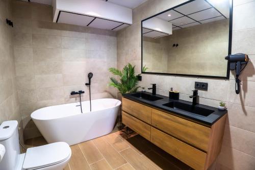 a bathroom with a tub and a sink and a toilet at Novaotel Malaga in Málaga