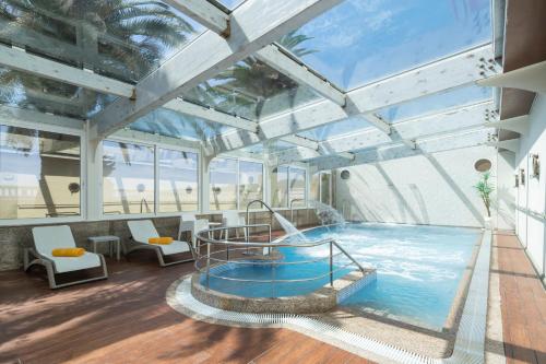 a large indoor swimming pool in a building at Eurostars Louxo Talaso in Isla de la Toja