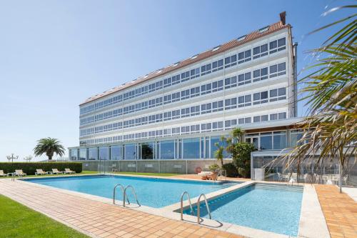 a building with a swimming pool in front of a building at Eurostars Louxo Talaso in Isla de la Toja