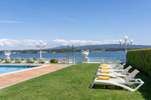 a row of lounge chairs on the grass next to a pool at Eurostars Louxo Talaso in Isla de la Toja