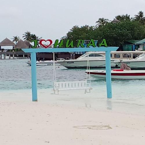 a sign on a beach with boats in the water at Seabreeze View - Huraa Island in Huraa