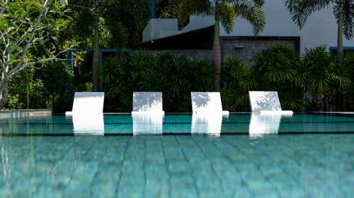 four white chairs sitting next to a swimming pool at Villa Lila in Ko Lanta