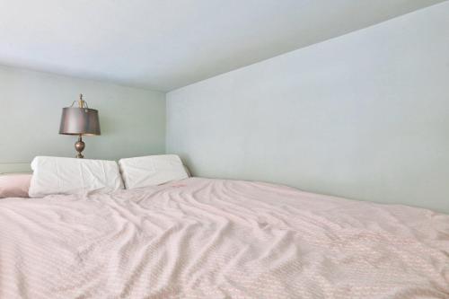 - une chambre blanche avec un lit rose et une lampe dans l'établissement 2 pièces Contemporain - La Chapelle Paris 18 - 2P, à Paris