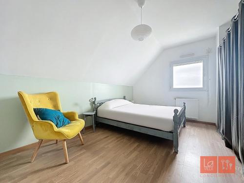 - une chambre avec un lit et une chaise jaune dans l'établissement Elléomazic, à Wimereux