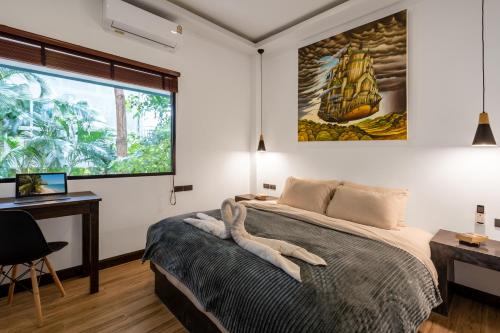 a bedroom with a bed and a desk and a window at Villa Lila in Ko Lanta