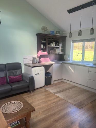 a living room with a couch and a kitchen at The Snuggery Broadclyst in Exeter