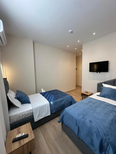 a bedroom with two beds and a tv on the wall at Luxury Hotel By Gjyshi in Qerrexhias