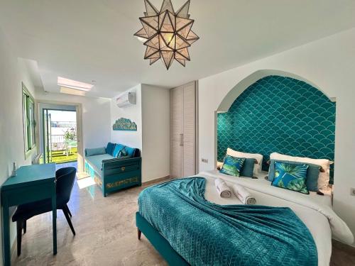 a bedroom with a bed with a blue headboard and a desk at Villa Verde Sidi Bou Said in Sidi Bou Saïd