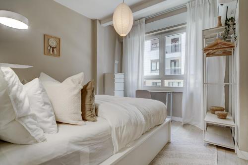 a white bedroom with a bed and a window at Gros Beach Heaven -Prime Location in Donostia-San Sebastián