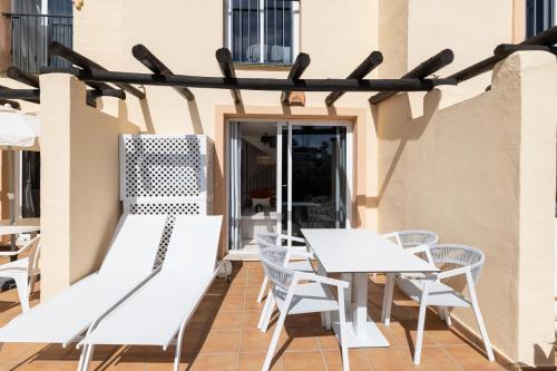 a patio with white chairs and tables on a building at Ramada Hotel & Suites by Wyndham Costa del Sol in Fuengirola