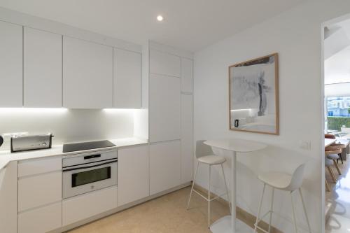 a white kitchen with a counter and stools at Ramada Hotel & Suites by Wyndham Costa del Sol in Fuengirola