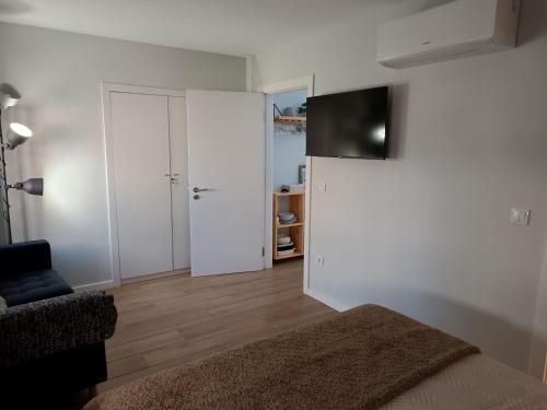 a bedroom with white walls and a bed and a tv at Cantinho das Quintãs in Viseu