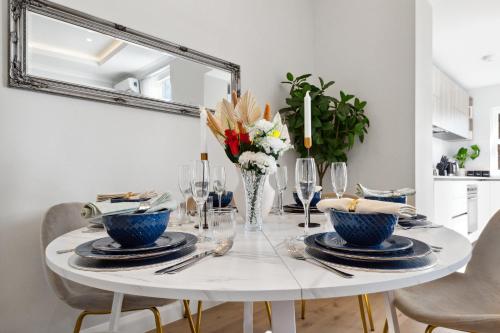 a white dining room table with blue dishes and a vase of flowers at The Notting Hill Villa in London