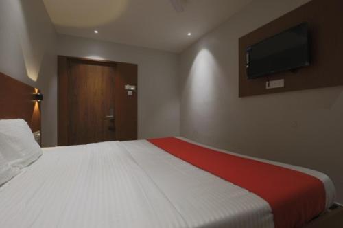 a bedroom with a large bed with a tv on the wall at Hotel Hi City Inn Near ISBT in Guwahati