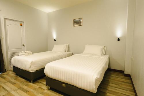 two beds in a small room with white sheets at The Ten Hotel Thippanate in Chiang Mai